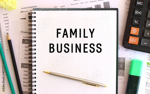 Notepad with text FAMILY BUSINESS on the office desk, near office supplies. Business concept.