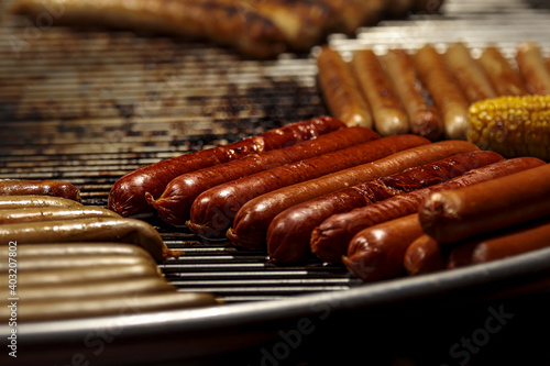 Grill sausage. Barbeque Bratwurst. Meet bbq party. Roasted pork and beer barbecue sausages sizzle on fire flame. Hot german gourmet lunch processed on round grill. Fatty and spicyrustic hotdog