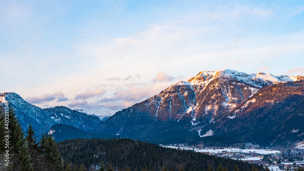 Obraz premium Mountain peaks during sunset against blue sky with orange fluffy clouds background.