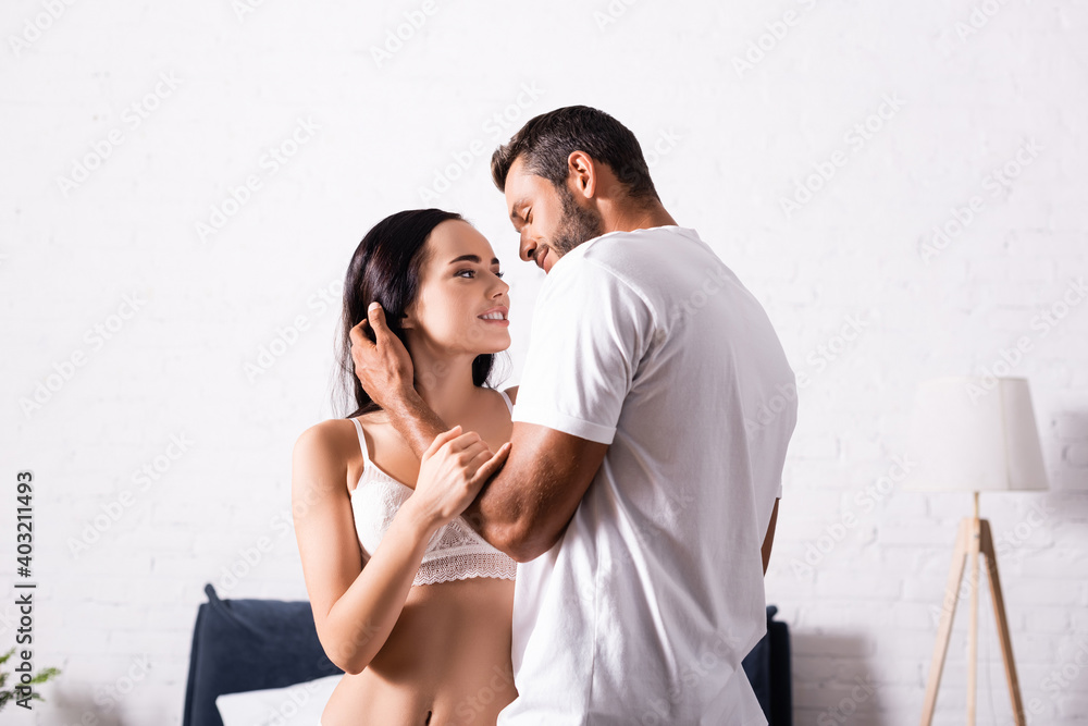 passionate young man looking and hugging at seductive woman in lingerie in bedroom passionate young man looking and hugging at seductive woman in lingerie in bedroom