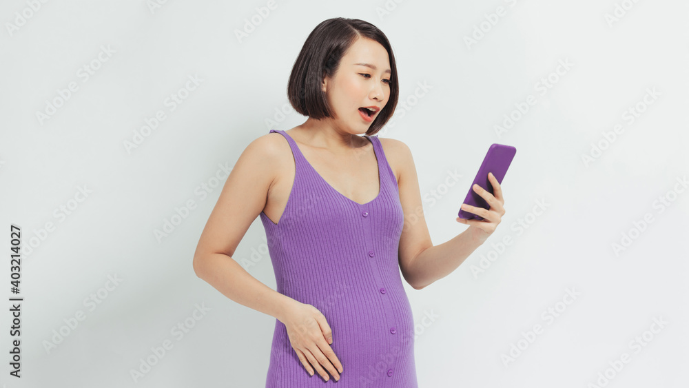 Amazed pregnant woman watching media content in a smart phone Amazed pregnant woman watching media content in a smart phone