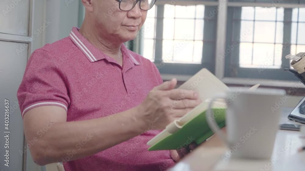 Asian senior man reading book sitting at home working desk, weekend free time leisure hobbies, mid adult male wear eye glasses, human eye sight problem, turning pages, focusing on one thing Asian senior man reading book sitting at home working desk, weekend free time leisure hobbies, mid adult male wear eye glasses, human eye sight problem, turning pages, focusing on one thing