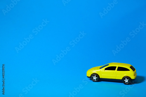 yellow toy car on blue background, concept idea of taxi and cargo delivery during quarantine © vadiar