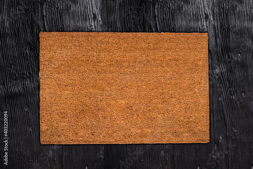 Natural coir doormat on antique wooden texture, background photo