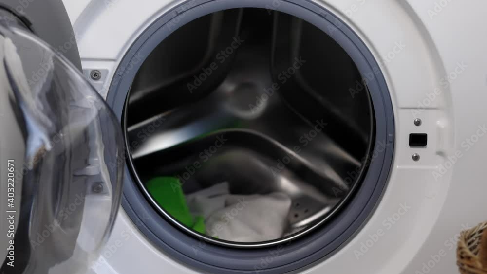Man's hand opening the front of the washing machine And is about to put the dirty laundry into the wash
Man's hand opening the front of the washing machine And is about to put the dirty laundry into the wash