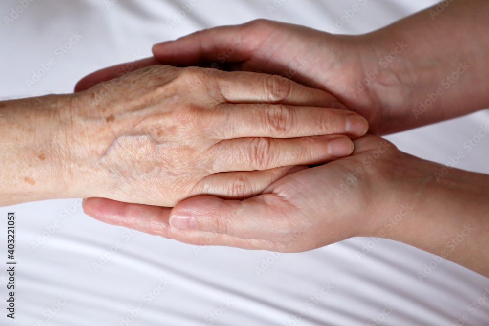 Wrinkled hands of senior woman in the palms of a young woman. Concept of care and support, elderly mother and daughter