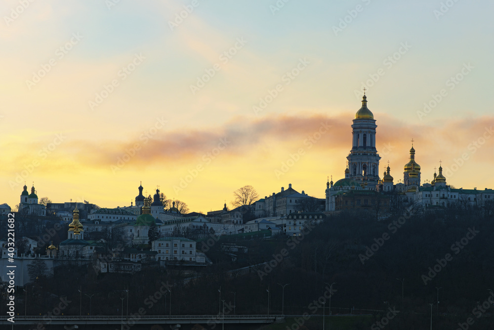 Scenic winter landscape view of famous Kyiv's hills against cloudy sky during sunset. Scenic landscape of ancient Kyiv Pechersk Lavra. It is a historic Orthodox Christian monastery. Kyiv, Ukraine