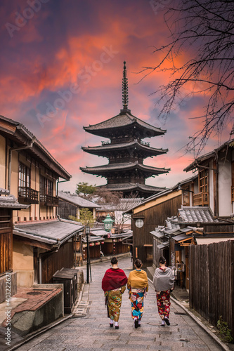 (Selective focus) Three unidentified women wearing kimono are walking on the path leading to the to the Kiyomizu-dera Temple (defocused in the distance) during a stunning sunset. Kyoto, Japan. © Travel Wild