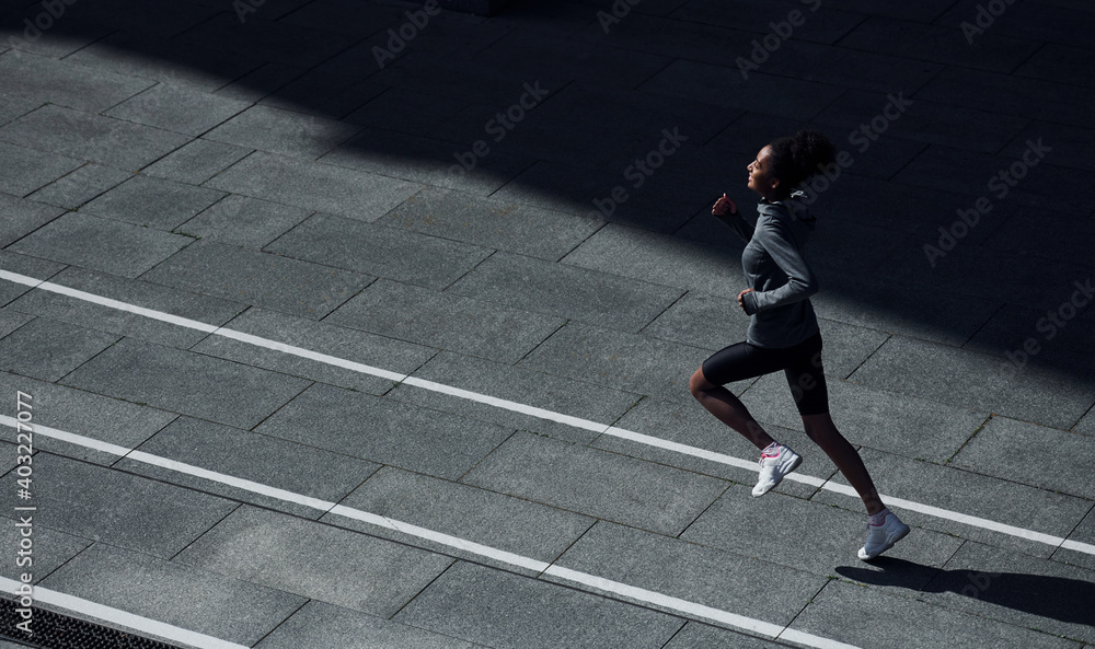 Fast runner. Young african american woman in sportive clothes have workout outdoors at daytime