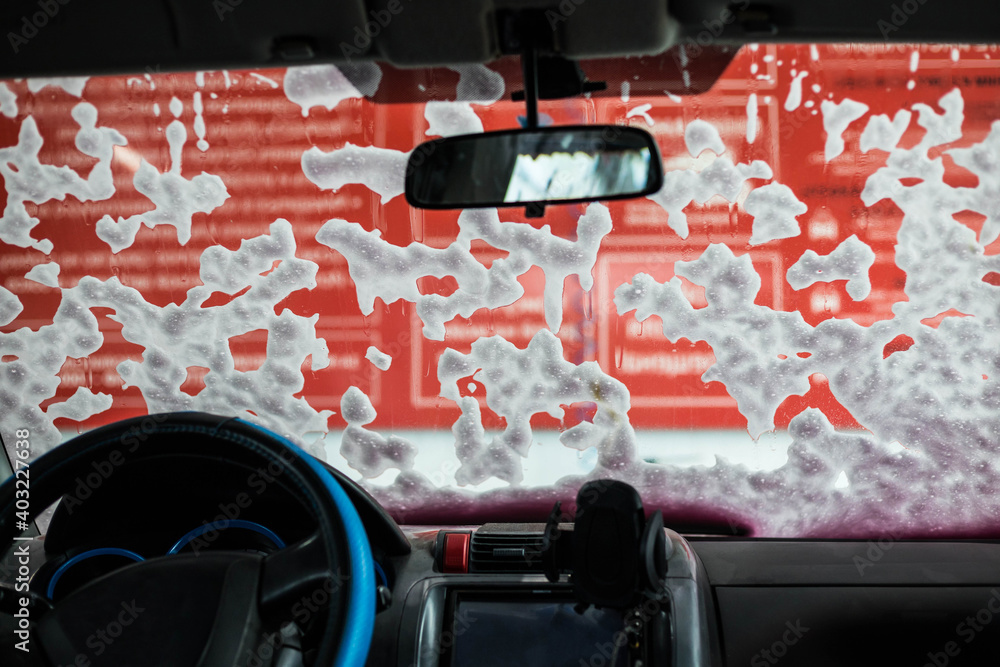 Naklejka premium Foam on the windshield of the car, the view from the inside. Car wash.
