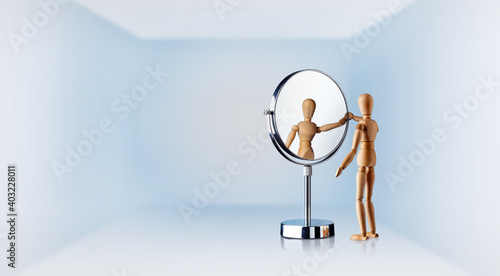 Holzfigur schaut in einen Spiegel 