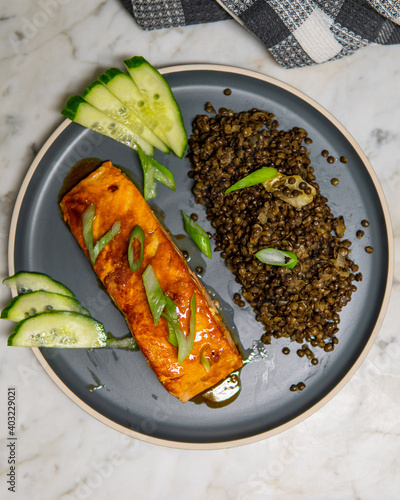 Delicious baked honey soy glazed salmon fillet served with black beluga lentils with Cucumber and green onions. Healthy fresh salmon steak for lunch or dinner. Top View