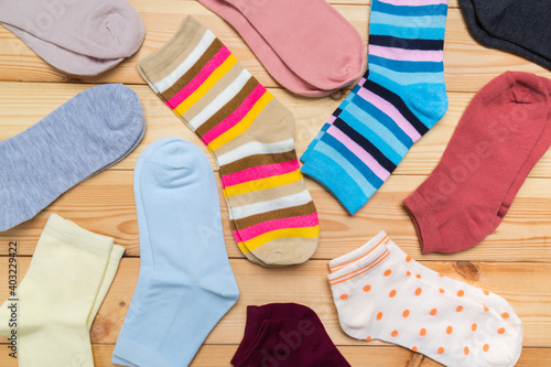 multicolored new socks in different sizes stacked on a wooden background. clothes for women