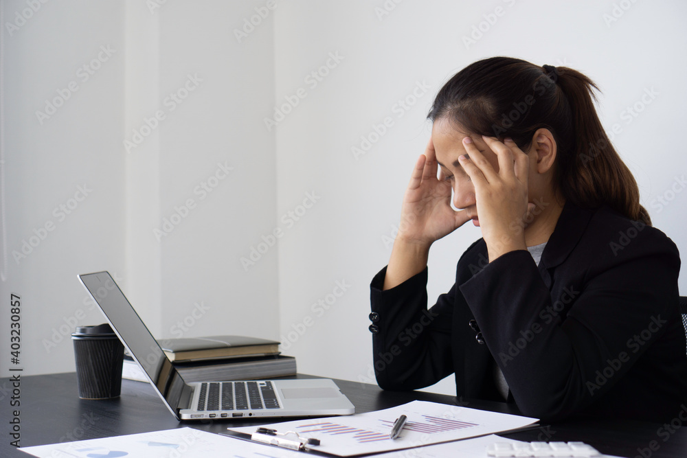 Portrait of a business woman stressed in front of her laptop And graph documents The company's performance shares fell at many points. At her desk office this morning Portrait of a business woman stressed in front of her laptop And graph documents The company's performance shares fell at many points. At her desk office this morning