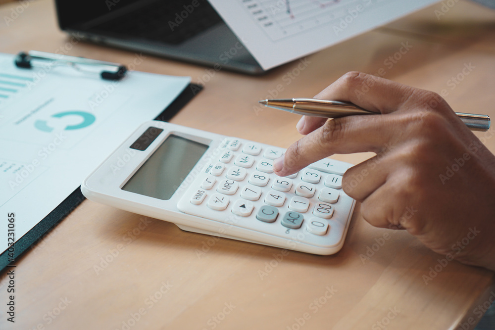 Asian male finance staff Calculating turnover with a calculator From the company's rapidly growing bar graph this year To propose to his master to listen On the desk at the office, Finance concept Asian male finance staff Calculating turnover with a calculator From the company's rapidly growing bar graph this year To propose to his master to listen On the desk at the office, Finance concept