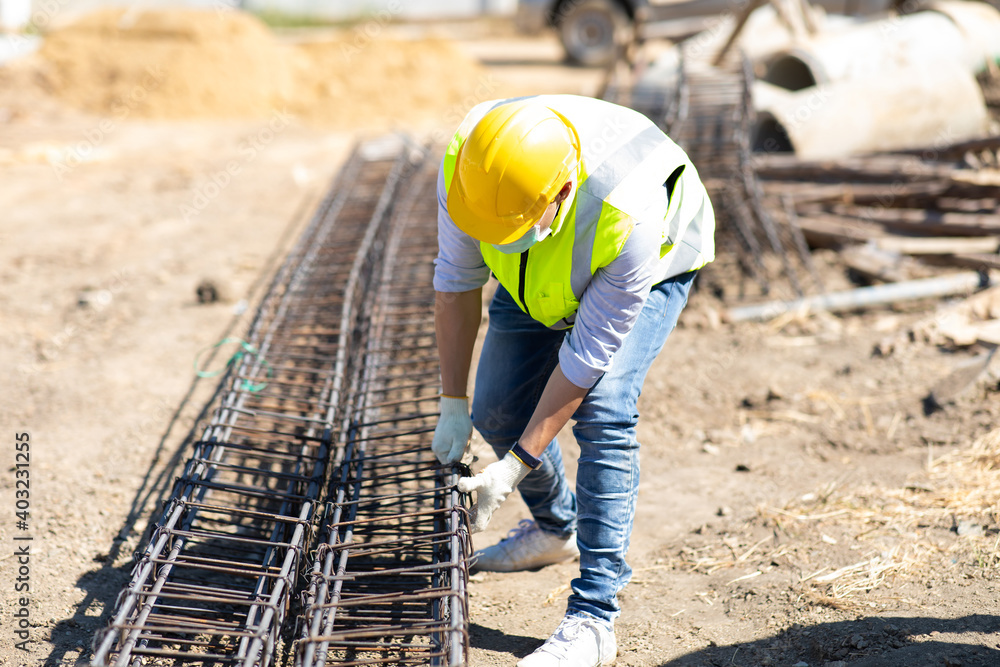 Asian construction worker on building site. fabricating steel reinforcement bar. wearing surgical face mask during coronavirus and flu outbreak Asian construction worker on building site. fabricating steel reinforcement bar. wearing surgical face mask during coronavirus and flu outbreak