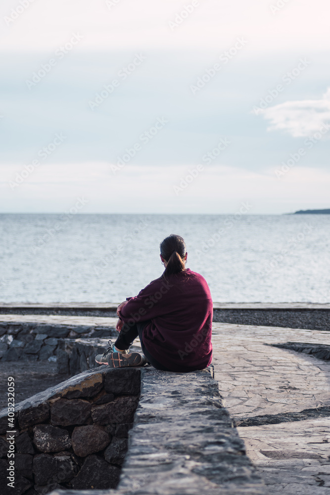 Woman sitting looking at the sea Woman sitting looking at the sea