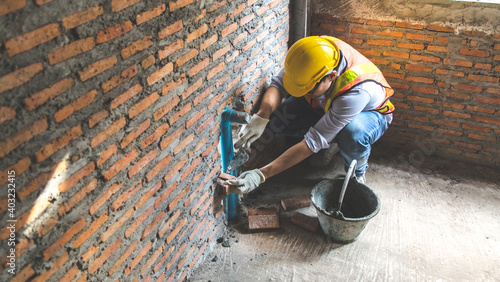 Man bricklayer installing bricks on construction site photo