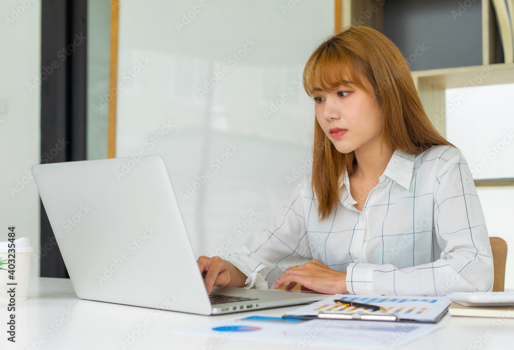 A female accountant is using a laptop to e-mail and check income accounts. Finance company expenditures In her office A female accountant is using a laptop to e-mail and check income accounts. Finance company expenditures In her office