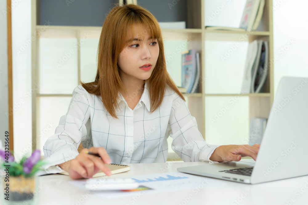 Asian female accountant Using a calculator to calculate company taxes For profit At her desk in the office this morning, corporate tax and profit ideas. Asian female accountant Using a calculator to calculate company taxes For profit At her desk in the office this morning, corporate tax and profit ideas.