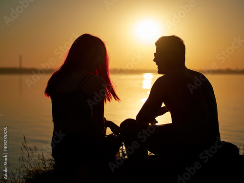 silhouette of a romantic loving couple at sunset. lake in the background