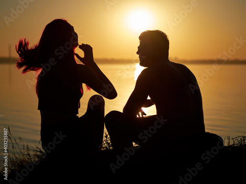 silhouette of a romantic loving couple at sunset. lake in the background