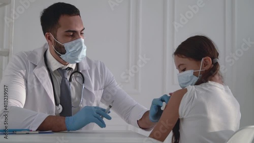 Male doctor administering a COVID-19 vaccine to a girl. Man giving an injection for the coronavirus.