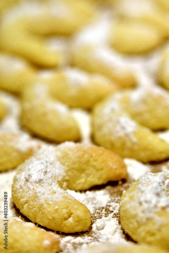 Closeup of freshly baked small crescent shaped vanilla cookies, vertical.