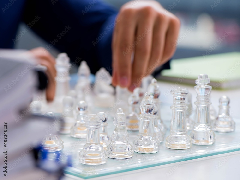 Young businessman playing glass chess in office Young businessman playing glass chess in office
