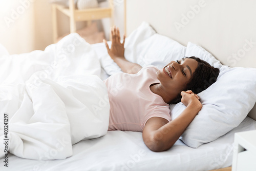 Happy young woman waking up in her bed