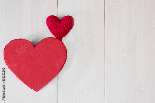 View from above. Two love symbol big red heart and small on a light pink wooden background with space for text. Valentine's day concept. Selective focus.