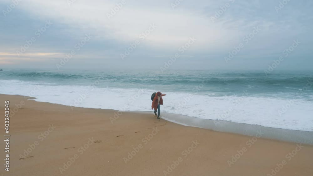 positive guy with big backpack runs away from foamy ocean waves rolling on sand beach at sunset slow motion positive guy with big backpack runs away from foamy ocean waves rolling on sand beach at sunset slow motion
