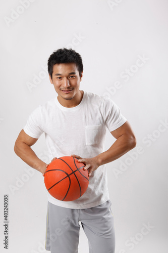 A young man playing basketball in casual clothes