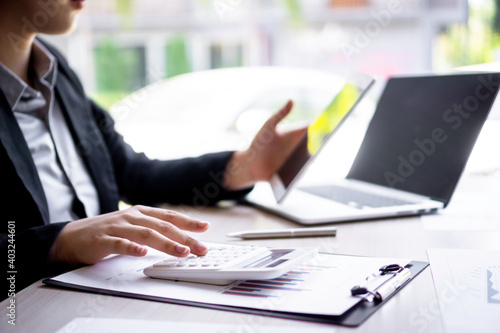 ..Female finance workers are using a calculator to calculate the company's earnings from a bar graph. That show the profit of the company At her desk in the office