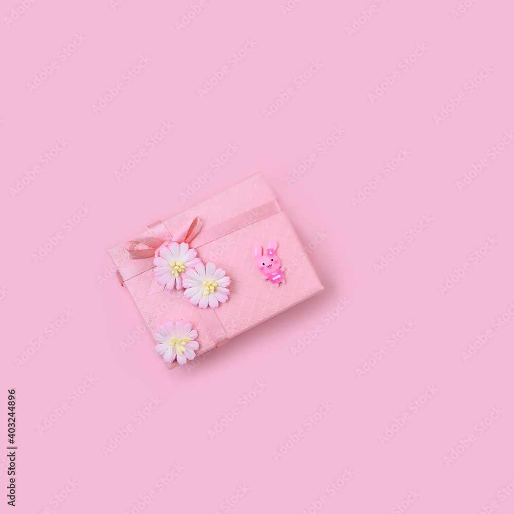 gift box for girl on pink background. Present box decorated with ribbon, flowers and small cute bunny toy. romantic gift concept