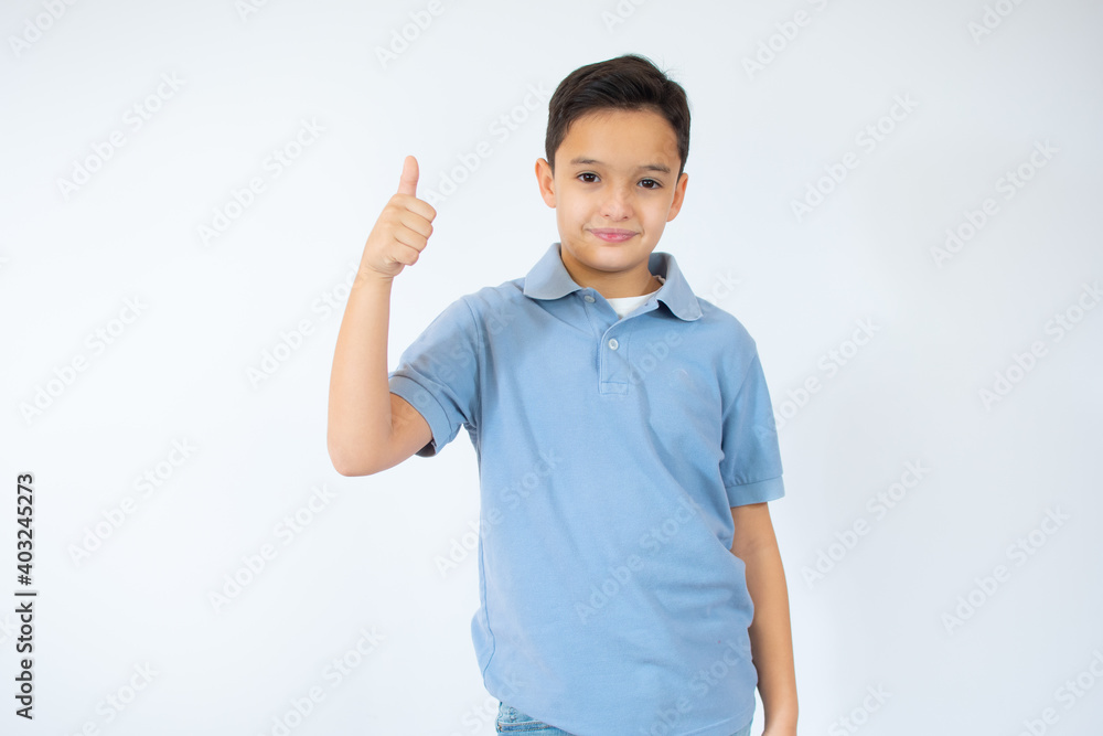 Happy child, little boy showing thumbs up gesture in a blue T-shirt isolated on white background Happy child, little boy showing thumbs up gesture in a blue T-shirt isolated on white background