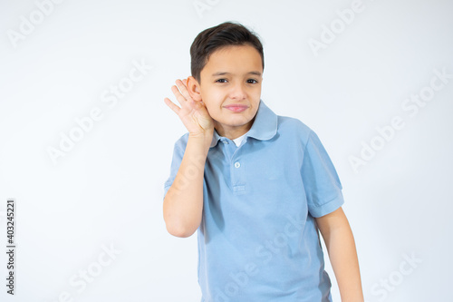 Boy in blue t-shirt making hearing gesture on white background. facial expression. kid with hand over ear listening gossip.