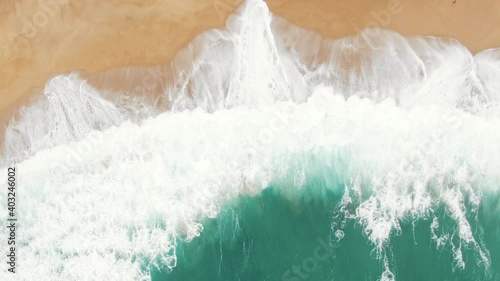 stunning aerial view of immense turquoise ocean huge waves washing yellow beach covering sand with foam photo