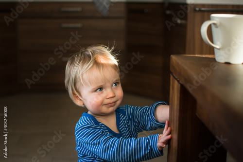 Wallpaper Mural Little child try to grab cup of hot drink on the table. Attention hot content concept. Torontodigital.ca