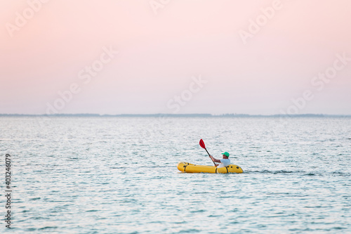 Distant view of man in the yellow colored boat that is in the sea © standret