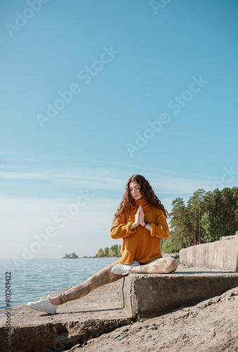 Woman in orange sweater sitting on a stone stairs on a beach