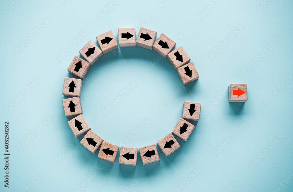 Disruption and technology transformation concept , Red arrow on wooden block cube move out from circle black arrow on blue background. Disruption and technology transformation concept , Red arrow on wooden block cube move out from circle black arrow on blue background.