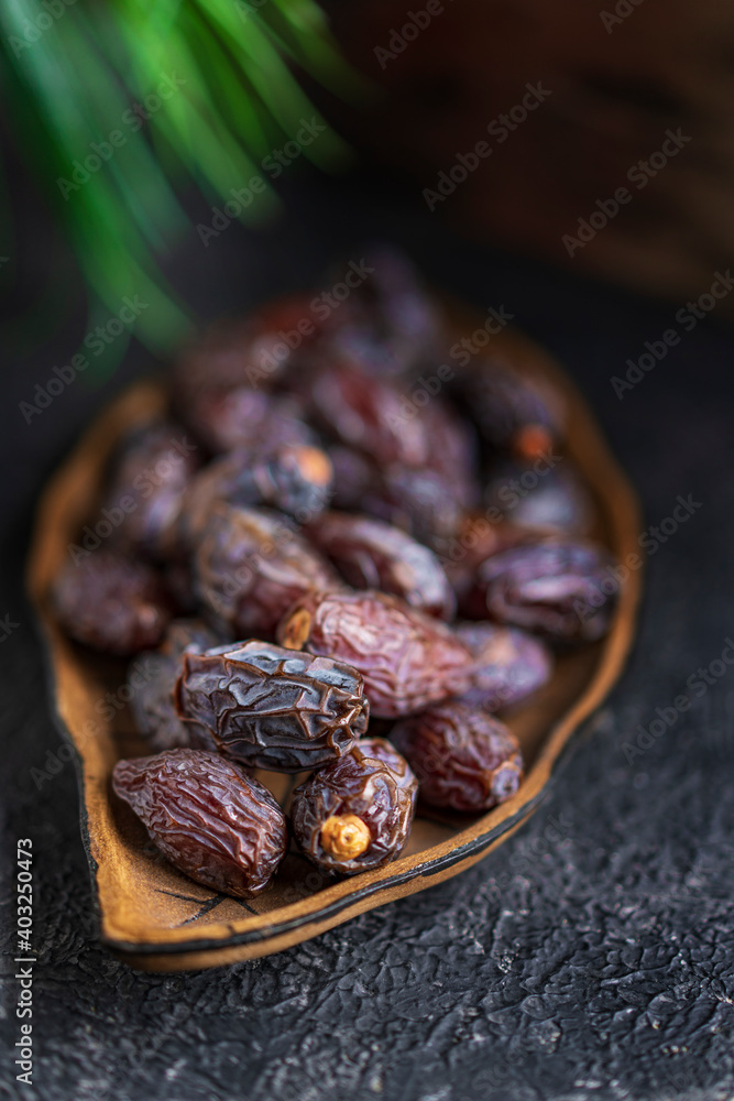 Selective focus or dried dates organic fruits on a plate plate, black textured table with copy space. Selective focus or dried dates organic fruits on a plate plate, black textured table with copy space.