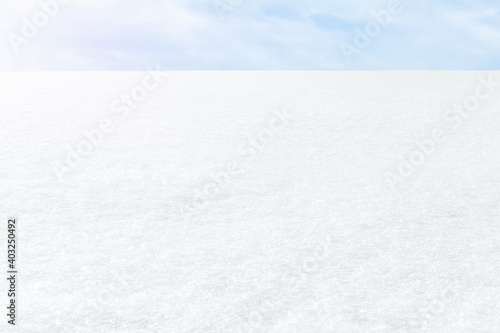 Fresh white snow on a blue sky background. Winter frosty landscape. Illuminated by the side sun. The horizon receding into the distance.
