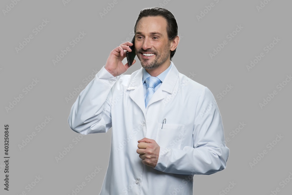 Happy doctor or scientist talking on cell phone. Male science engineer talking on mobile phone against gray background. Happy doctor or scientist talking on cell phone. Male science engineer talking on mobile phone against gray background.