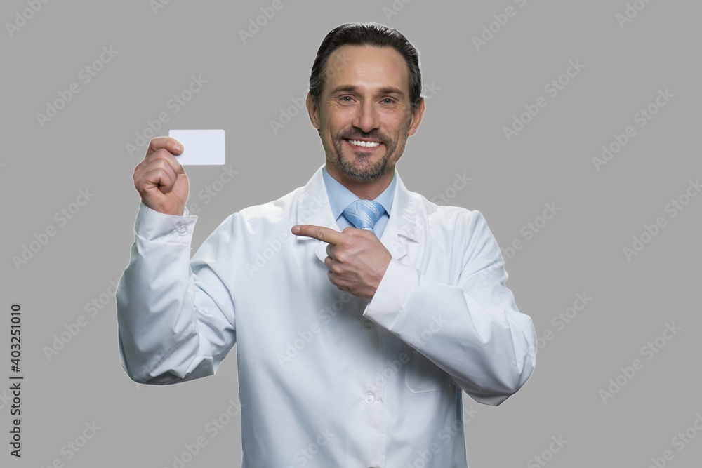 Male scientist pointing on business card. Medical worker showing business card and looking at camera against gray background. Male scientist pointing on business card. Medical worker showing business card and looking at camera against gray background.