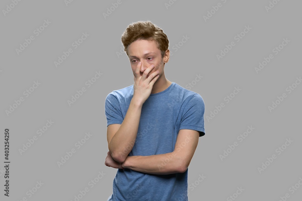 Portrait of upset teenage boy against gray background. Young sad teenager man looking pensive. Concerned about mistake. Portrait of upset teenage boy against gray background. Young sad teenager man looking pensive. Concerned about mistake.