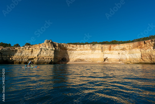 father and twho young children paddle on a SUP board along the Algarve coast in Portugal