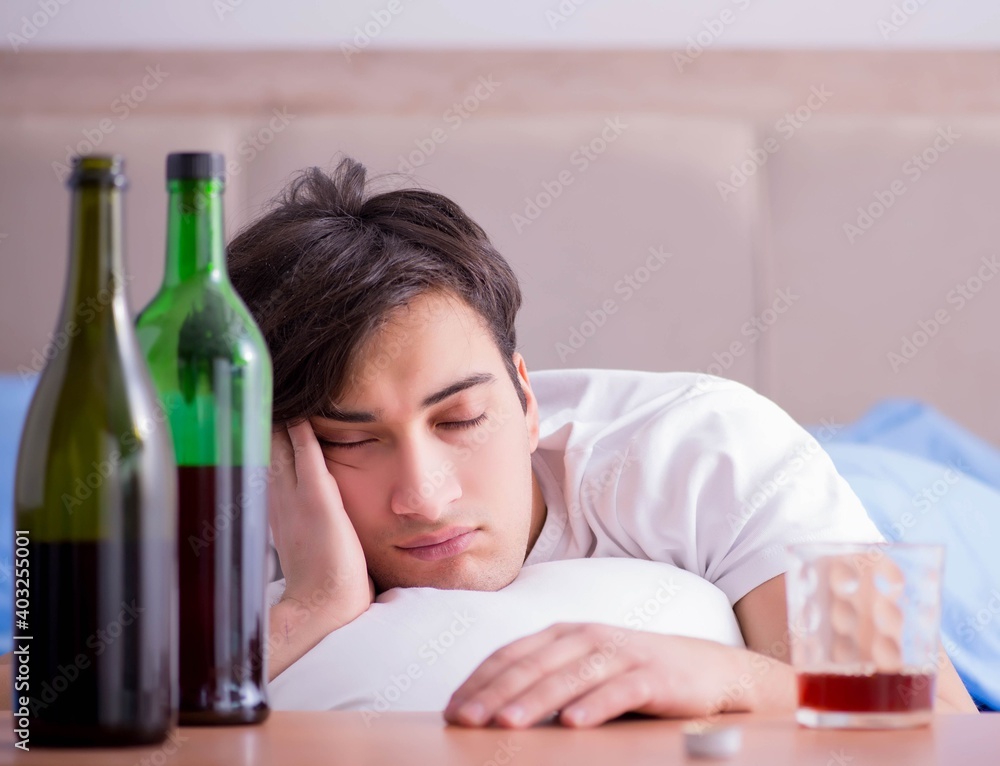 Man alcoholic drinking in bed going through break up depression Man alcoholic drinking in bed going through break up depression