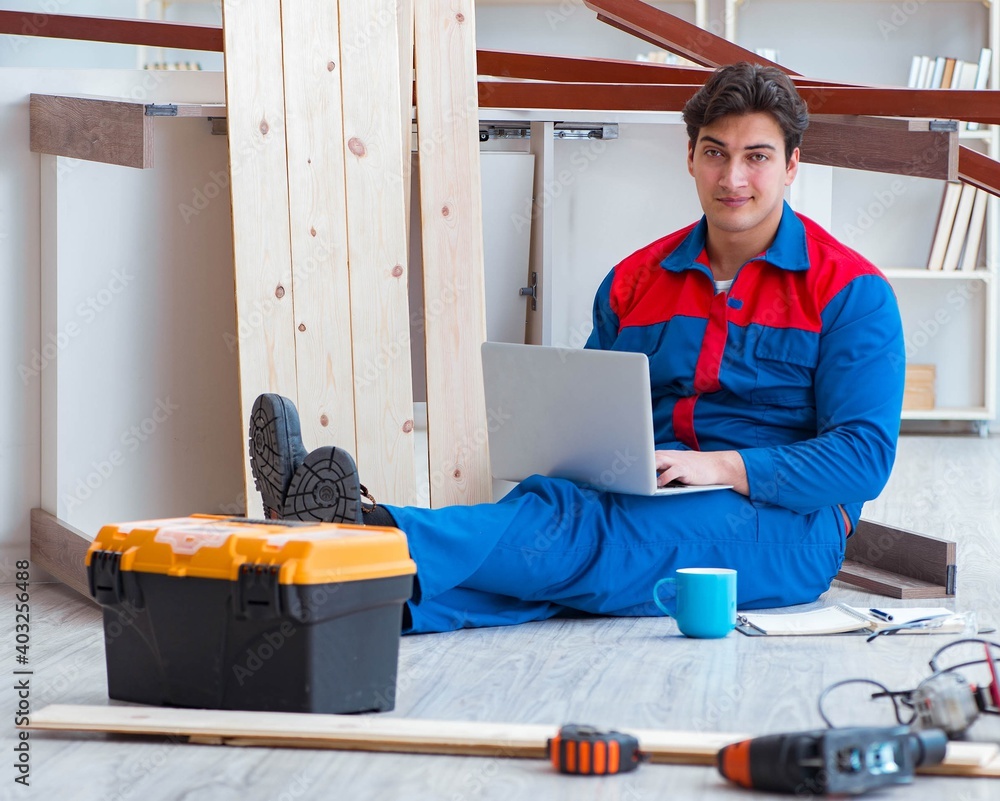 Young carpenter with a laptop computer Young carpenter with a laptop computer